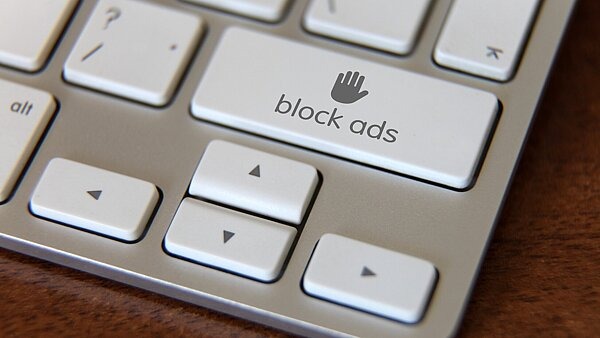 Ausschnitt einer Computertastatur mit einer speziellen Taste, auf der „block ads“ und ein Stoppsymbol (Hand) steht – symbolisch für das Blockieren von Glücksspiel-Werbung im Internet.