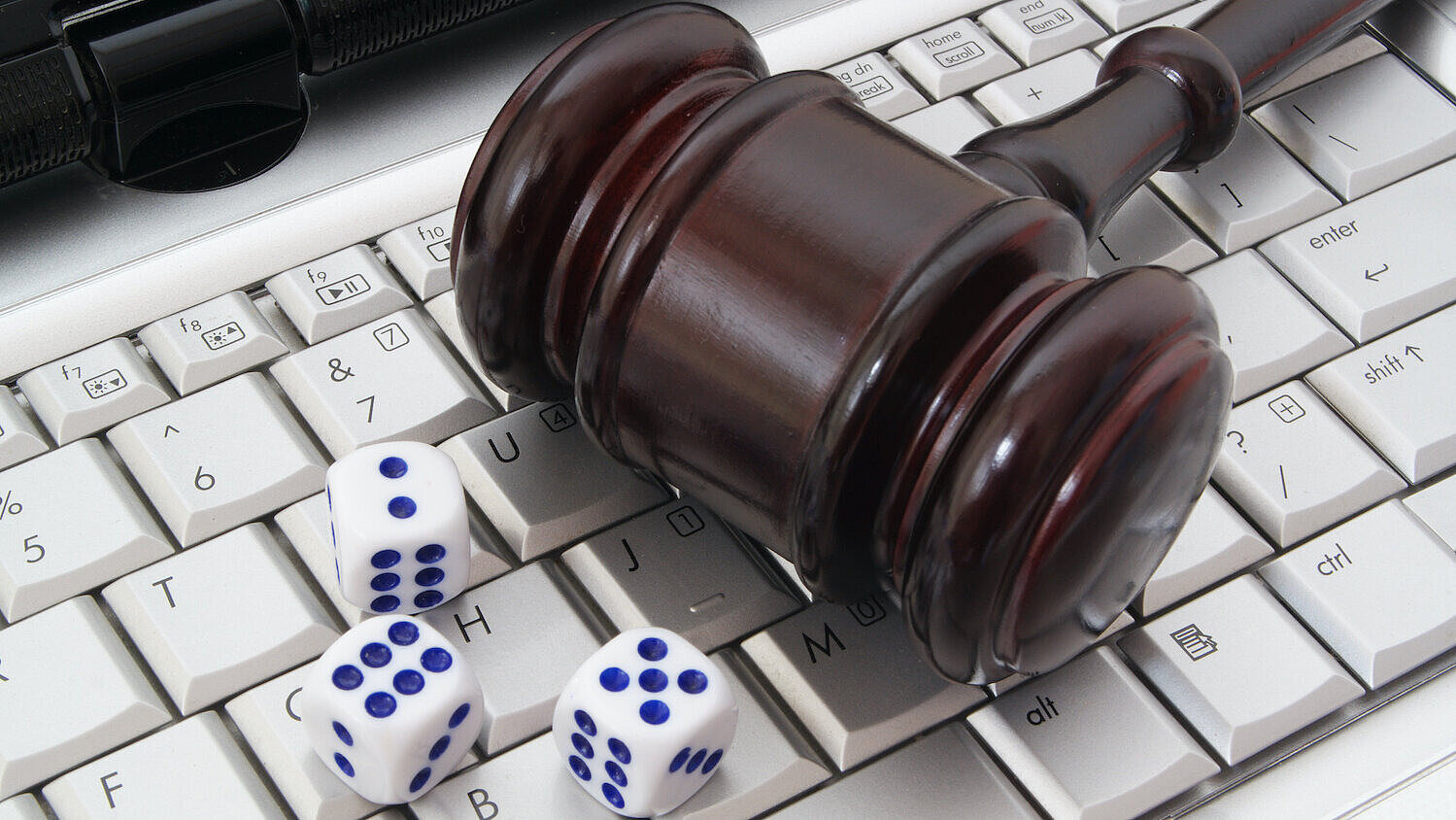 Richterhammer und Würfel liegen auf einer Laptop-Tastatur